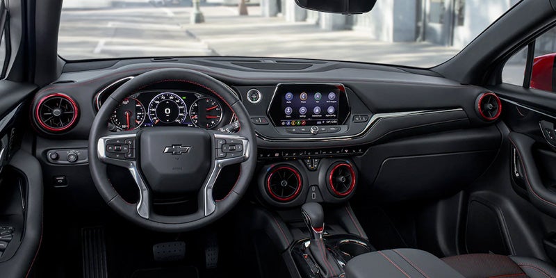 View of the 2022 Chevy Blazer dashboard from the drivers perspective. Steering wheel, temperature controls, center console and gear shift are visible.