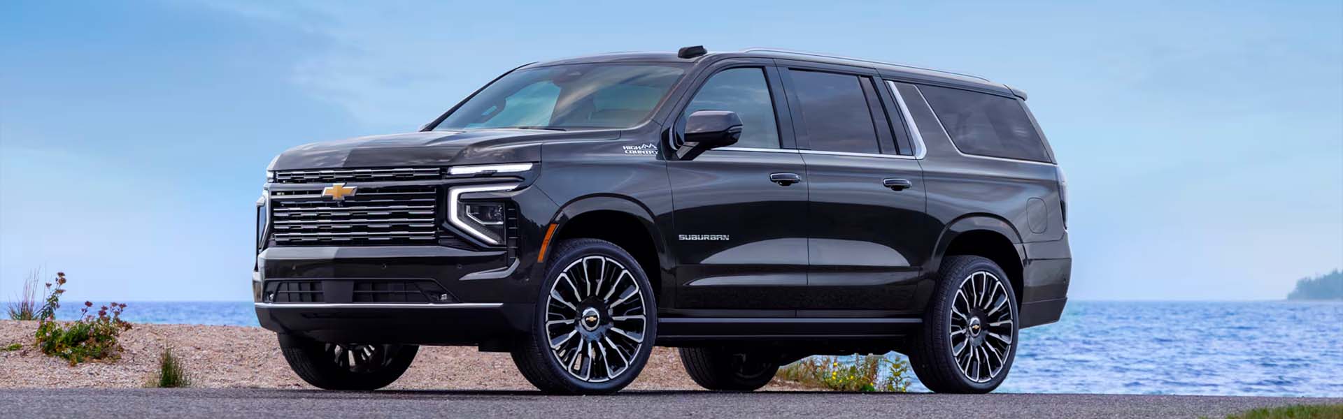 Front side view of the 2025 Chevy Suburban parked in front of a beach