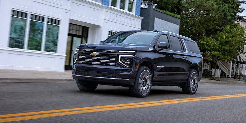 Front side view of the 2025 Chevrolet Suburban driving on a suburban street