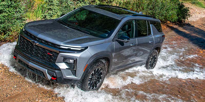 2025 Chevrolet Traverse driving through water on a gravel trail