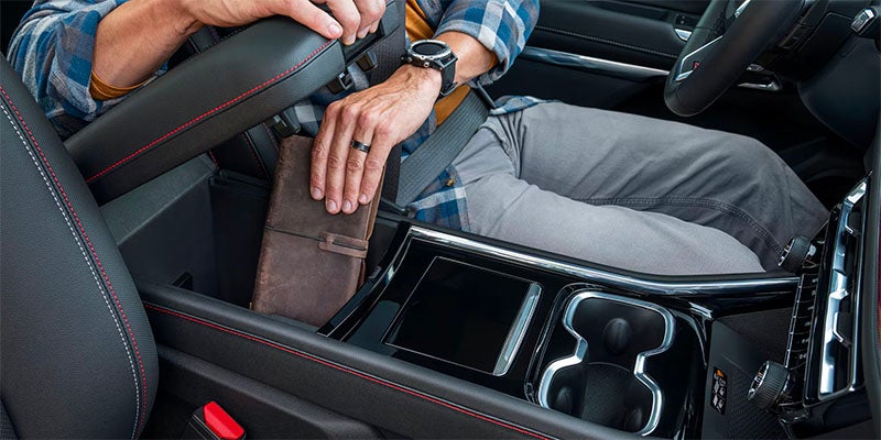 Close up view of driver opening the center console to store a large wallet