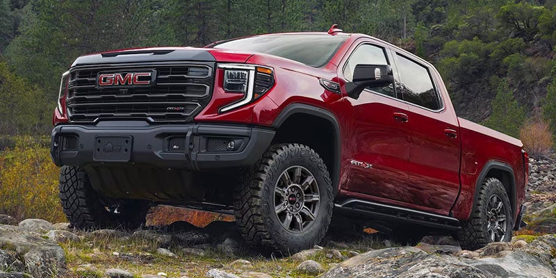 Side view of GMC Sierra 1500 driving over large rocks