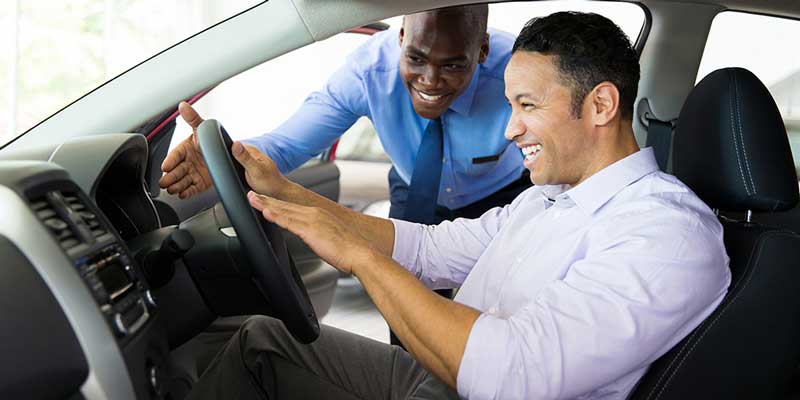 Stock image of a customer on a test drive with a salesperson